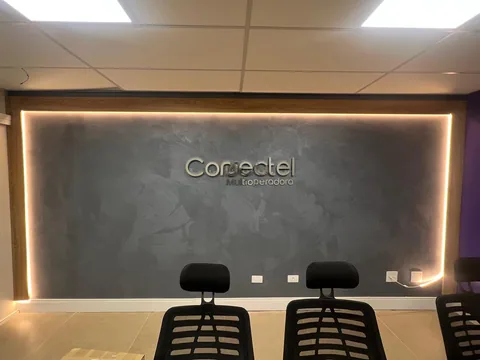 Identificação Conectel na parede da recepção, com iluminação no contorno do ambiente