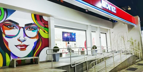 Fachada Ótica Diniz com letreiro vermelho e adesivação gráfica junto à entrada